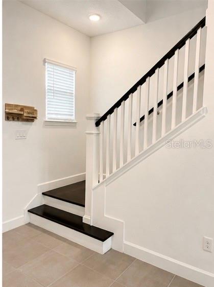 An entryway features a staircase with dark wood treads, white risers, and a black handrail — 12632 CLEAR SAPPHIRE DRIVE, WINTER GARDEN, FL
