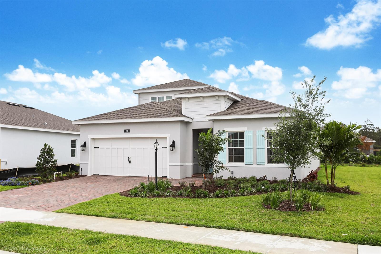 A single-story house with a white garage, light blue shutters, and a brick driveway — 84 Jetty Lane, Sebastian FL 32958, SEBASTIAN, FL