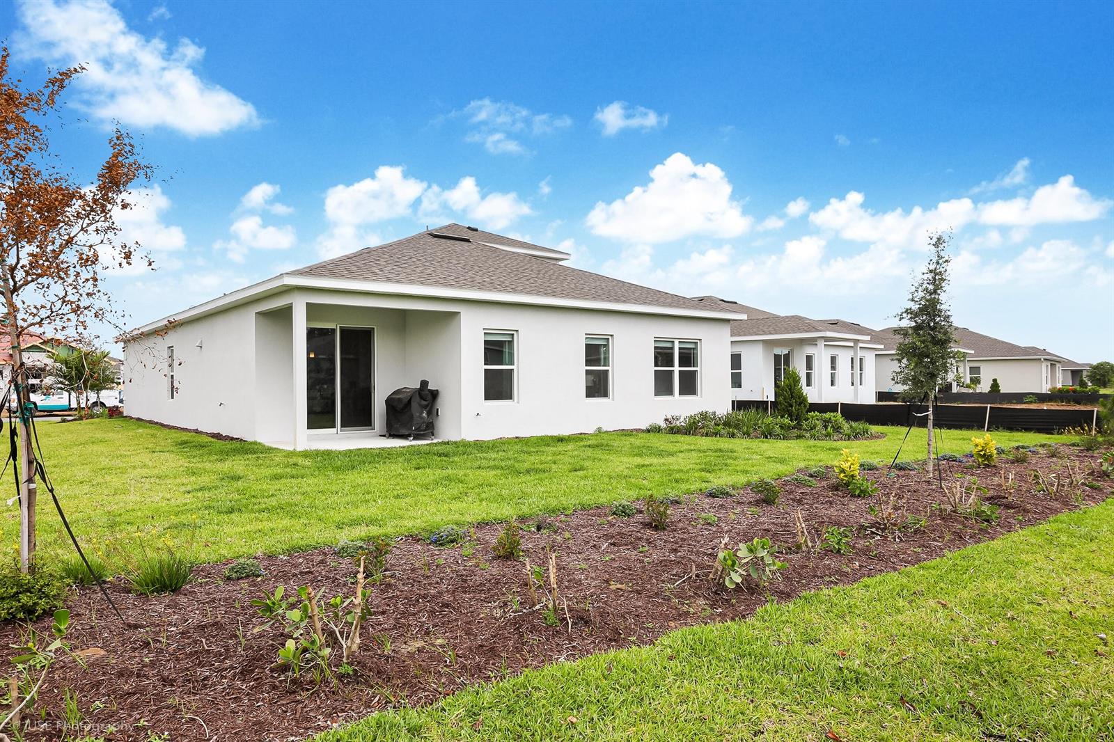The exterior rear view of a white single-story house with a patio and lawn — 84 Jetty Lane, Sebastian FL 32958, SEBASTIAN, FL