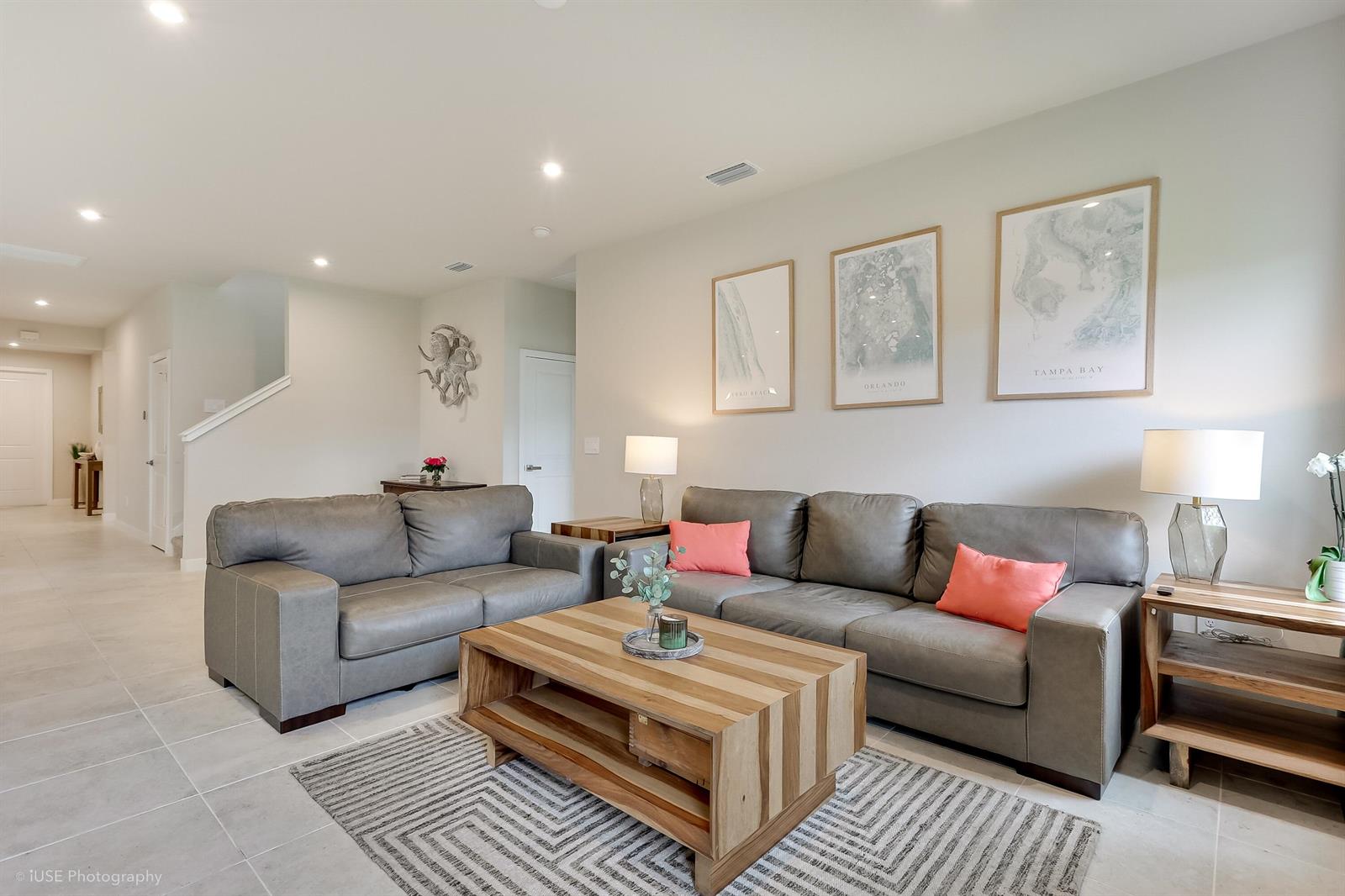 A living room features two gray leather sofas, a wooden coffee table, and framed maps — 84 Jetty Lane, Sebastian FL 32958, SEBASTIAN, FL