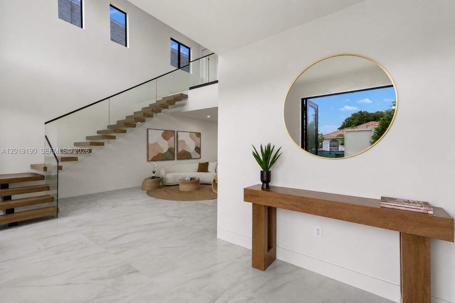 A modern entryway features a floating wooden staircase, white marble floors, and a console table — 2265 SW 4 St, Miami FL 33135, MIAMI, FL