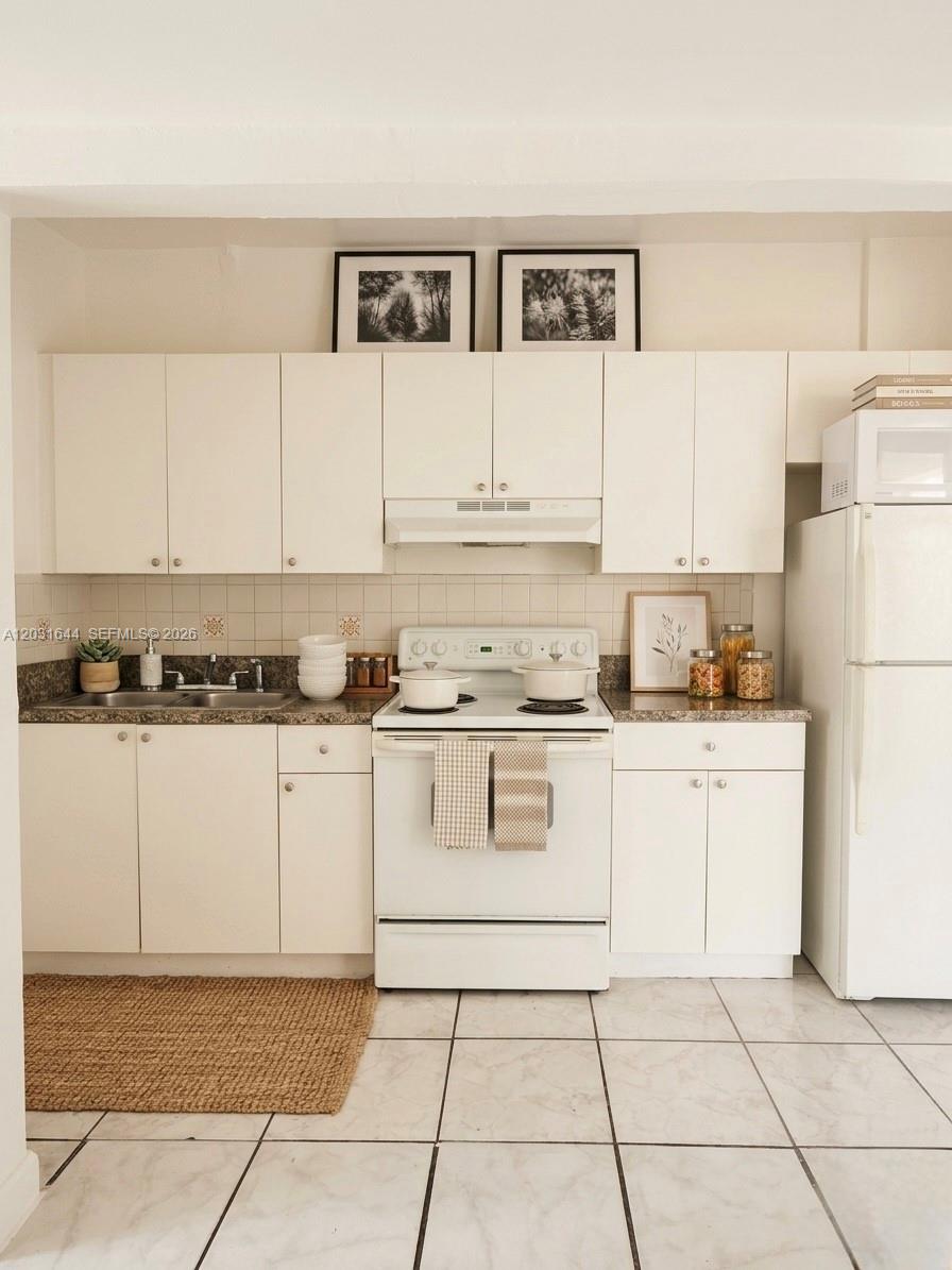 A kitchen features white cabinets, a white stove, a granite countertop, and tiled flooring — 2745 W Okeechobee Rd # 5, Hialeah FL 33010, HIALEAH, FL
