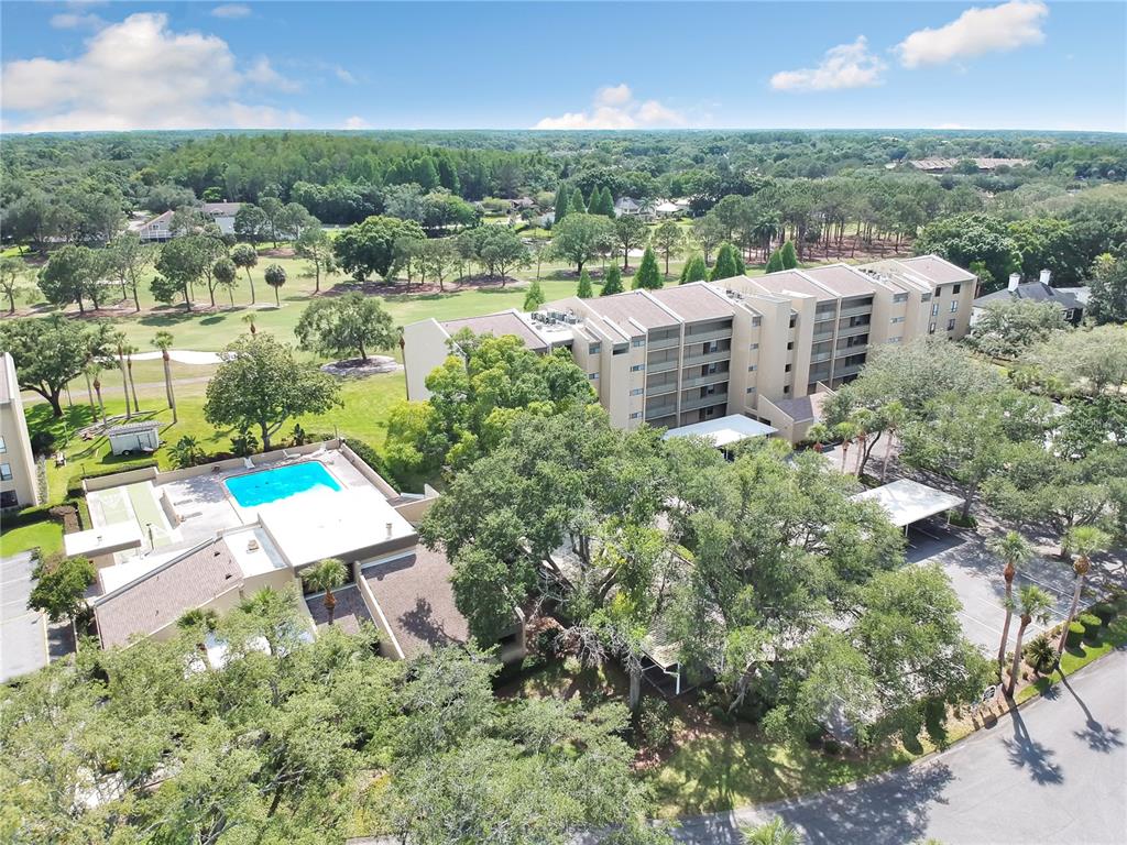 An aerial view shows a multi-story apartment building, a swimming pool, and surrounding trees — 13626 GREENFIELD DRIVE UNIT 201, TAMPA, FL