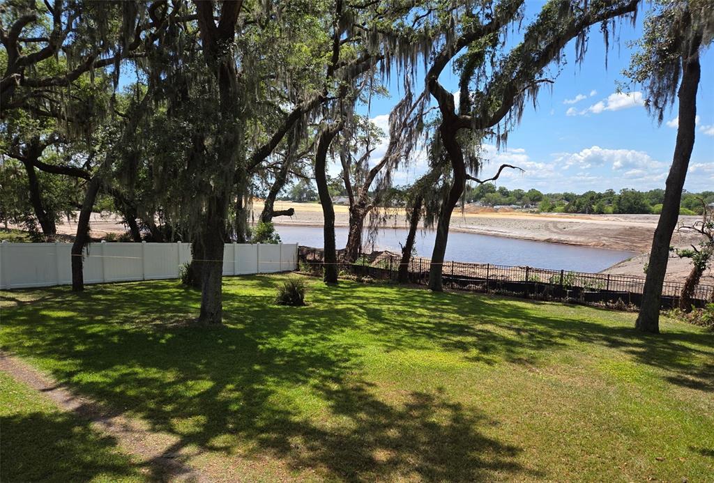 A grassy backyard with mature trees overlooks a pond and a construction site — 34041 HIGHLAND ROAD, LEESBURG, FL