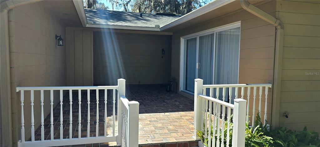 A brick patio with white railings sits in the corner of a tan house exterior — 34041 HIGHLAND ROAD, LEESBURG, FL