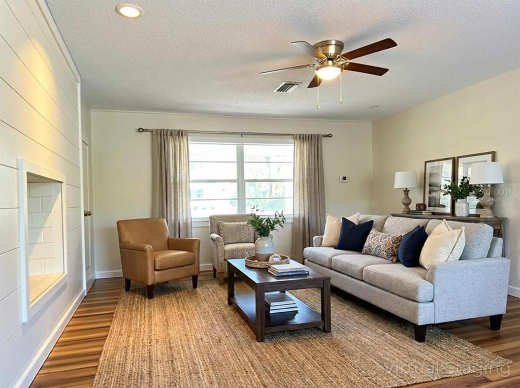 A living room features a light gray sofa, leather armchair, coffee table, and wood flooring — 34041 HIGHLAND ROAD, LEESBURG, FL