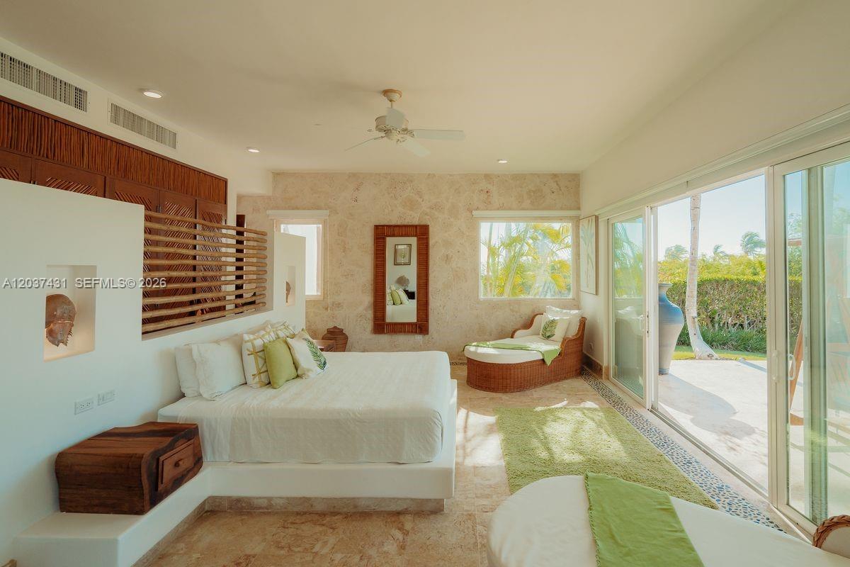 A bedroom features a platform bed, stone walls, a wicker chaise lounge, and sliding glass doors — 0 Caleton estate, FL, FL