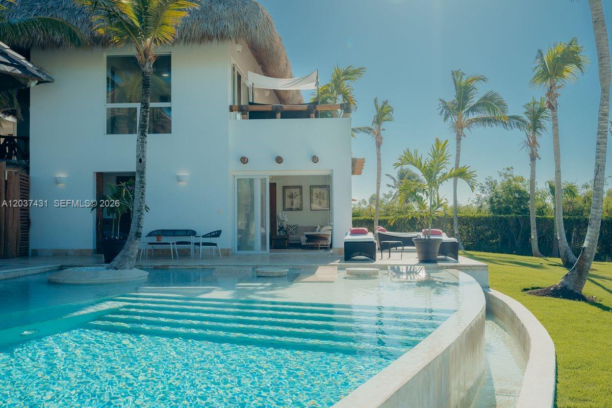 A white two-story house with a thatched roof overlooks a curved swimming pool and lawn — 0 Caleton estate, FL, FL