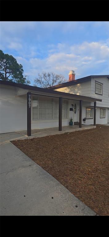 A white two-story house features a covered front porch with dark brown support posts — 7907 W HIAWATHA STREET, TAMPA, FL