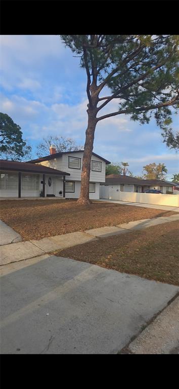 A two-story white house with a large pine tree in the front yard — 7907 W HIAWATHA STREET, TAMPA, FL