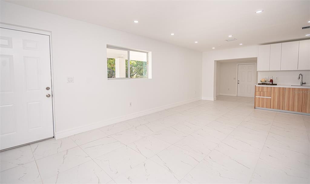 A bright, open-concept room features white walls, marble-patterned tile flooring, and a small kitchenette — 20720 NW 34 AVENUE, MIAMI GARDENS, FL