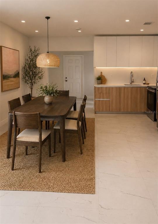 A dining area with a wooden table and chairs sits next to a modern kitchen — 20720 NW 34 AVENUE, MIAMI GARDENS, FL