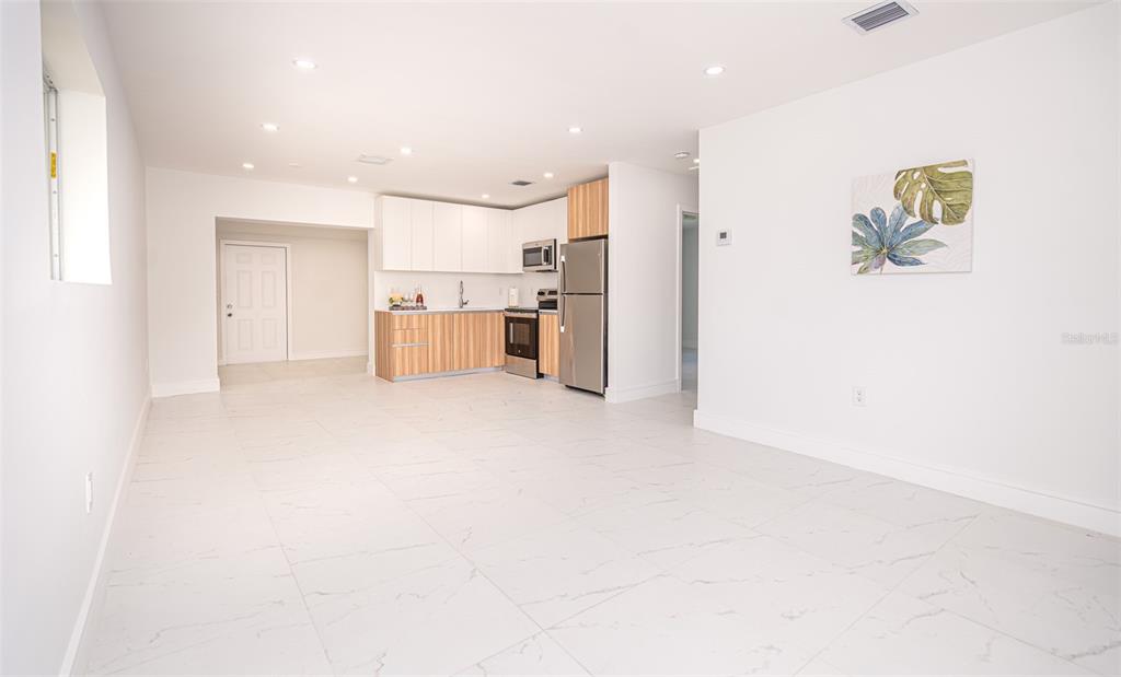 A modern kitchen with white and wood cabinetry sits in an open-concept room with tile — 20720 NW 34 AVENUE, MIAMI GARDENS, FL