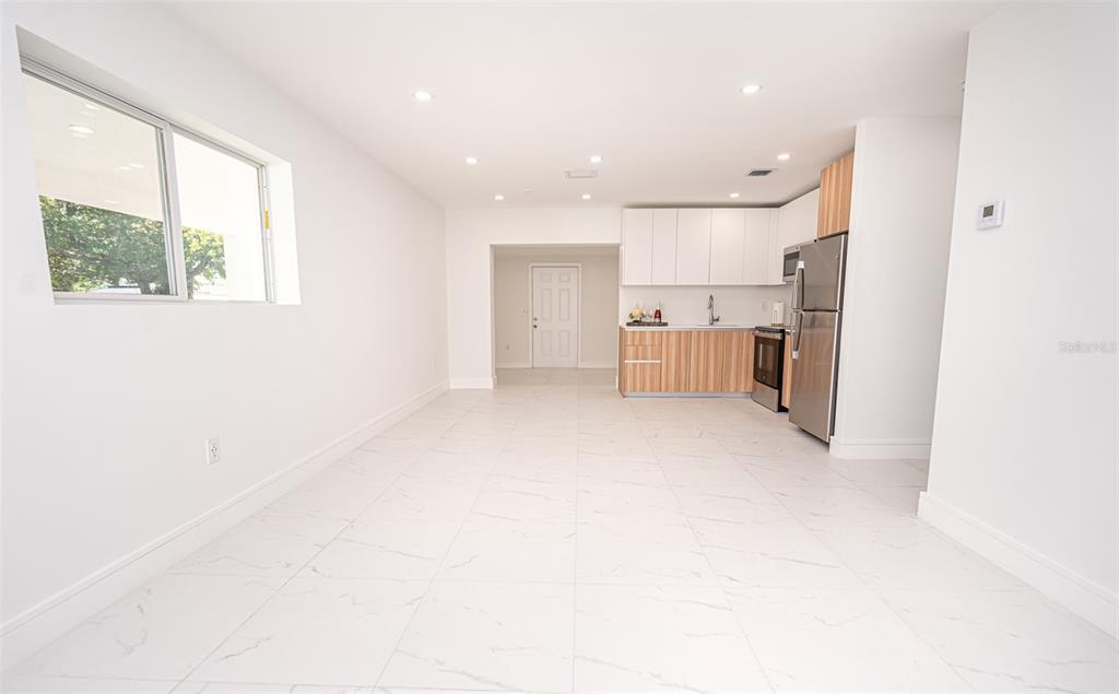 A bright, open-concept room features white marble-look tile floors and a modern kitchen — 20720 NW 34 AVENUE, MIAMI GARDENS, FL