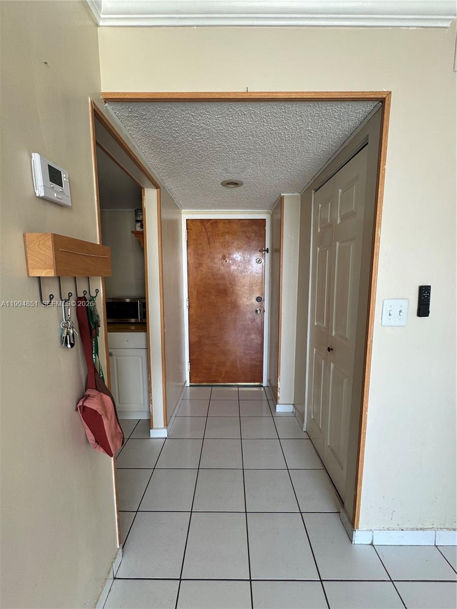 A tiled hallway leads to a wooden front door with a closet on the right — 2055 SW 122nd Ave # 403, Miami FL 33175, MIAMI, FL