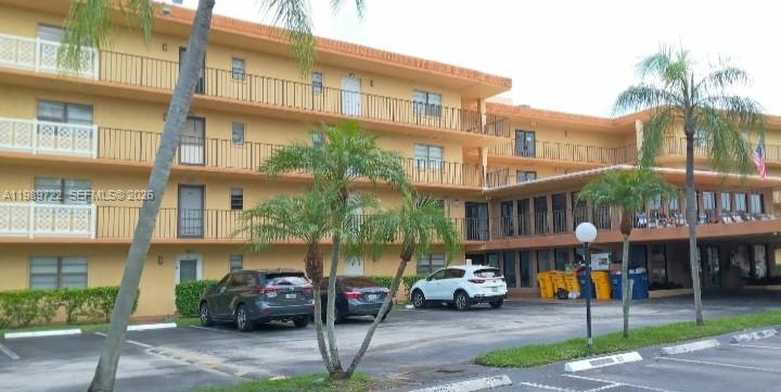 A three-story yellow apartment building with balconies and a parking lot in front — 9273 SW 8th St # 220, Boca Raton FL 33428, BOCA RATON, FL