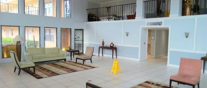 A spacious lobby features light blue walls, tile flooring, a seating area, and a mezzanine level — 9273 SW 8th St # 220, Boca Raton FL 33428, BOCA RATON, FL