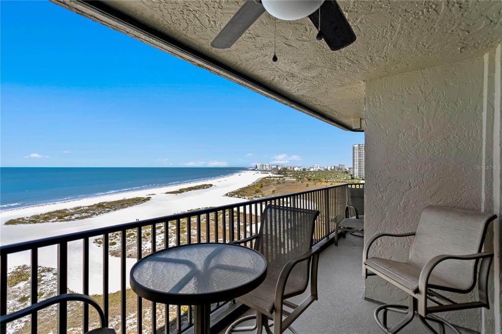 An aerial view shows high-rise condominiums situated along a sandy beach and the ocean — 1290 GULF BOULEVARD UNIT 1002, CLEARWATER, FL