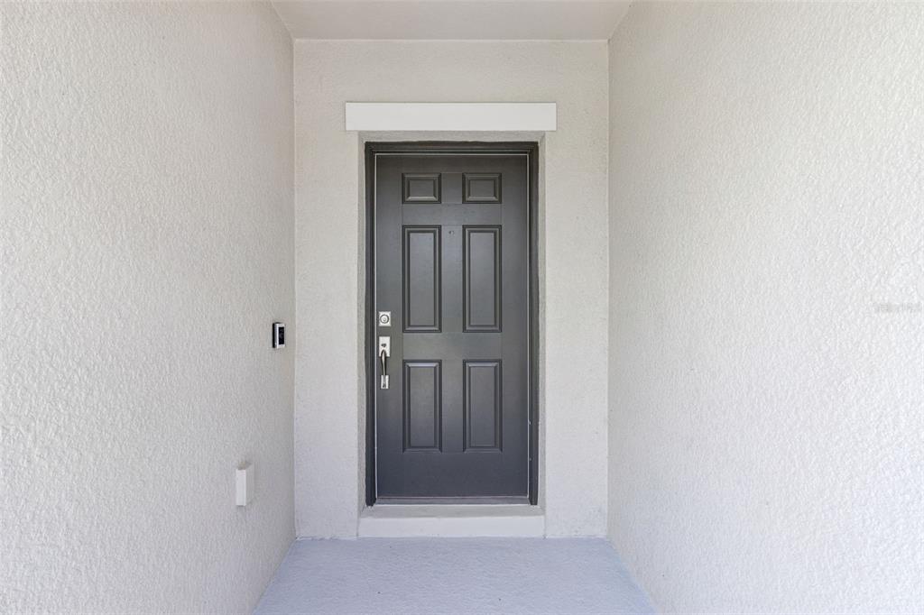 A dark gray six-panel front door is centered within a white stucco entryway — 309 CITRINE LOOP, KISSIMMEE, FL