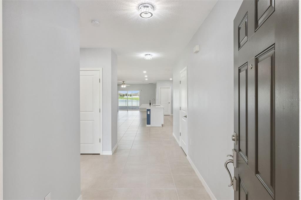A view from an entryway looking down a hallway toward a kitchen and living area — 309 CITRINE LOOP, KISSIMMEE, FL