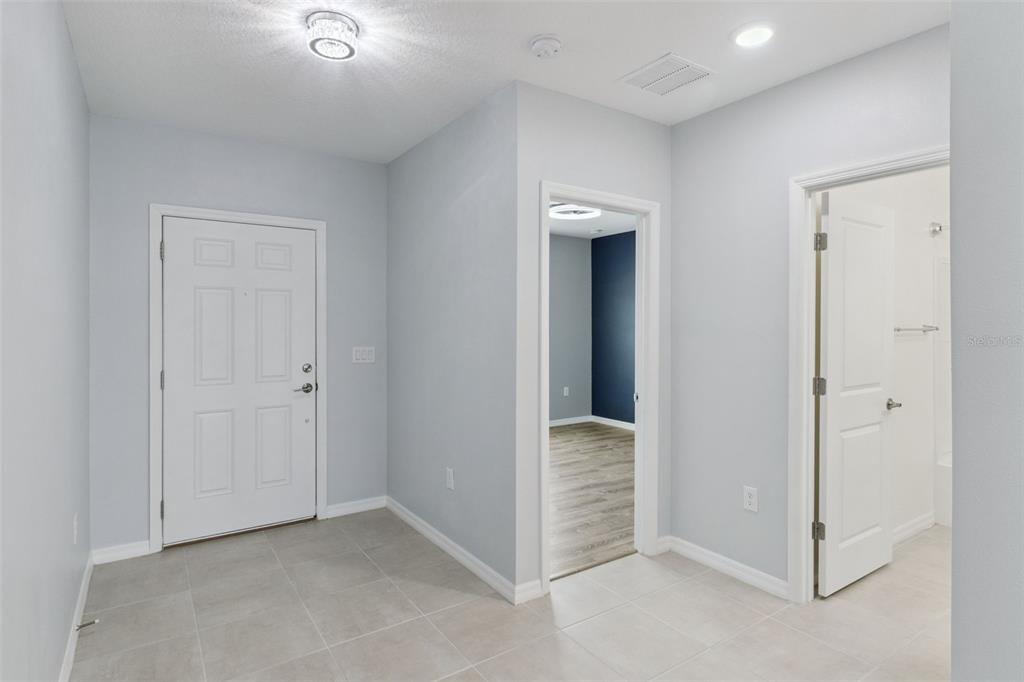 A tiled entryway features a white door, a doorway to a room, and a bathroom — 309 CITRINE LOOP, KISSIMMEE, FL