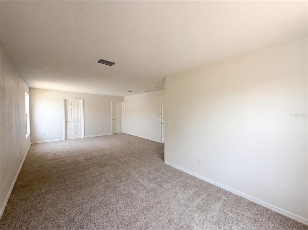 An empty room with beige carpet, white walls, and three closed interior doors — 8116 RIVER MONT WAY, TEMPLE TERRACE, FL