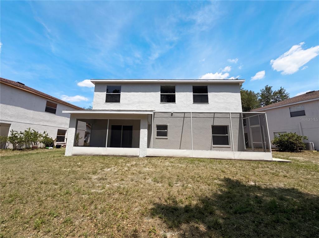 The rear exterior of a two-story house features a screened-in patio and a grassy yard — 8116 RIVER MONT WAY, TEMPLE TERRACE, FL
