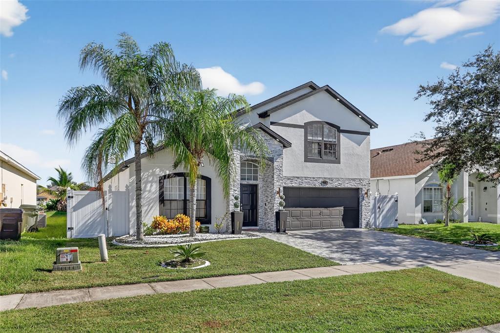A two-story house with a stone facade, a two-car garage, and a palm tree — 738 HACIENDA CIRCLE, KISSIMMEE, FL