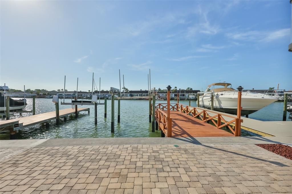 A paved patio overlooks a wooden boat dock and a canal with moored boats — 574 BOCA CIEGA POINT BOULEVARD N UNIT 2205, ST PETERSBURG, FL