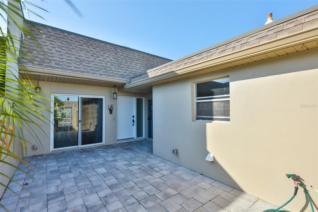 A paved patio area sits in the corner of a house with a sliding door — 574 BOCA CIEGA POINT BOULEVARD N UNIT 2205, ST PETERSBURG, FL
