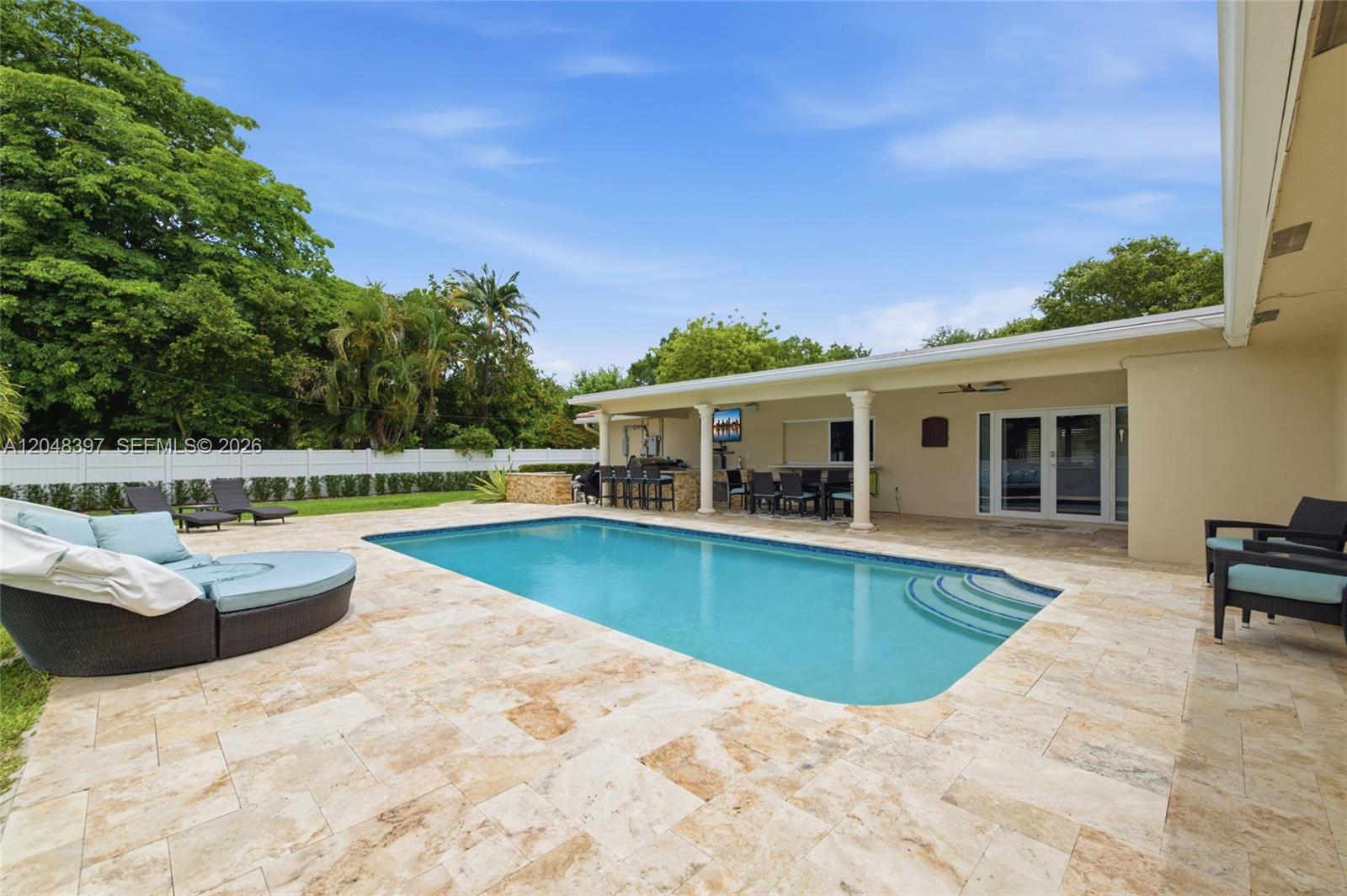 A backyard patio features a swimming pool, outdoor kitchen, and lounge furniture under a roof — 621 NW 74th Ave, Plantation FL 33317, PLANTATION, FL