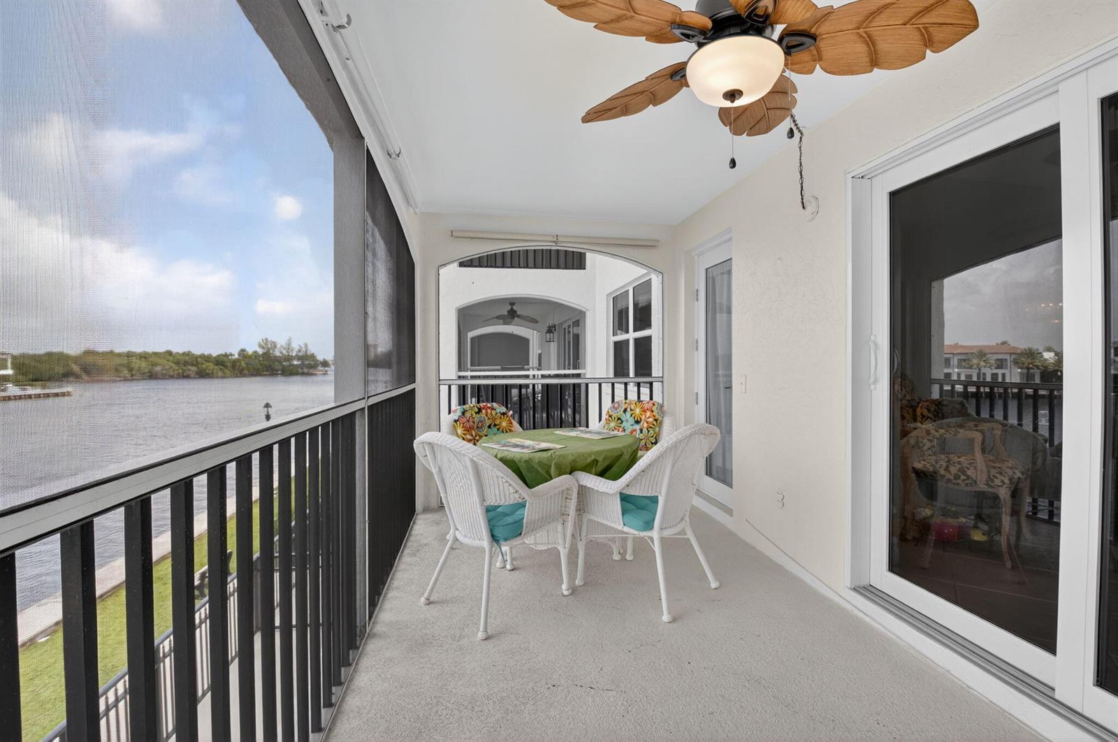 A screened-in balcony features a dining set, a ceiling fan, and a waterfront view — 2871 N Ocean Boulevard # R254, Boca Raton FL 33431, BOCA RATON, FL