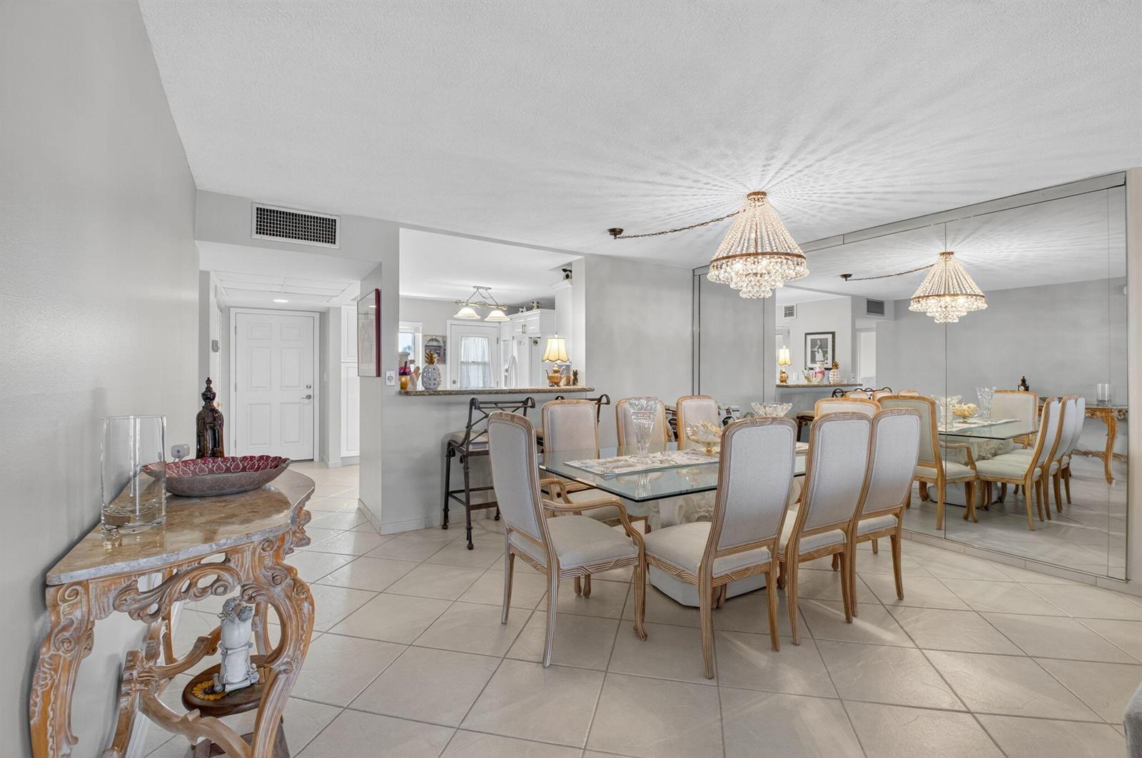 A dining room with a glass table, six chairs, a crystal chandelier, and mirrored walls — 2871 N Ocean Boulevard # R254, Boca Raton FL 33431, BOCA RATON, FL