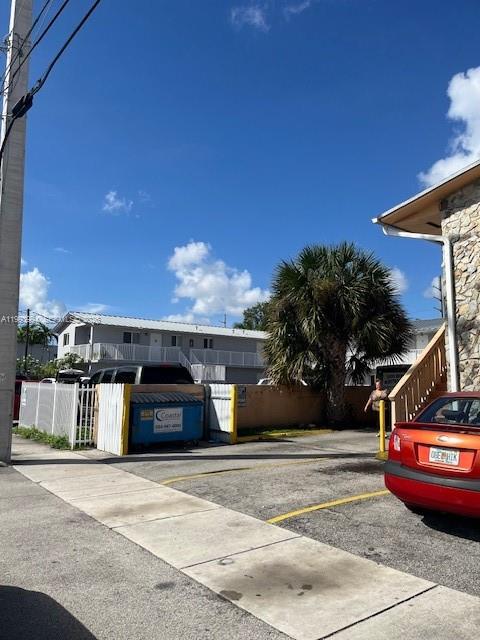 A view of a parking lot with a dumpster, a palm tree, and a building — 1151 W 28th St # 9, Hialeah FL 33010, HIALEAH, FL