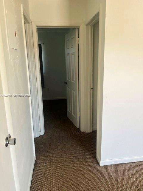 A hallway with brown carpet leads to an open doorway showing a bedroom — 1151 W 28th St # 9, Hialeah FL 33010, HIALEAH, FL
