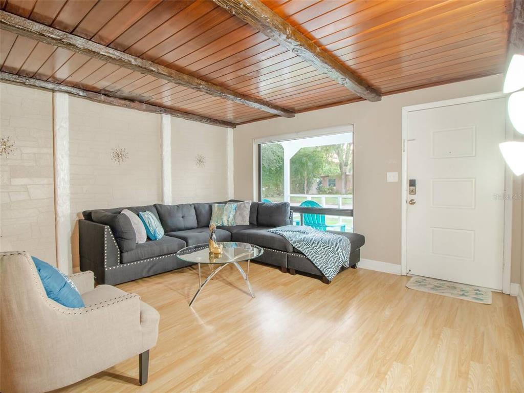 A living room features a wood-paneled ceiling, light wood flooring, and a gray sectional sofa — 1245 CATALPA LN UNIT 1, ORLANDO, FL