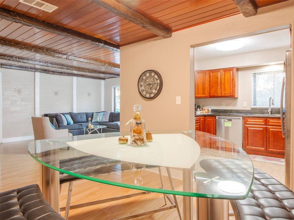 A glass-topped dining table sits in the foreground, with a living room and kitchen beyond — 1245 CATALPA LN UNIT 1, ORLANDO, FL