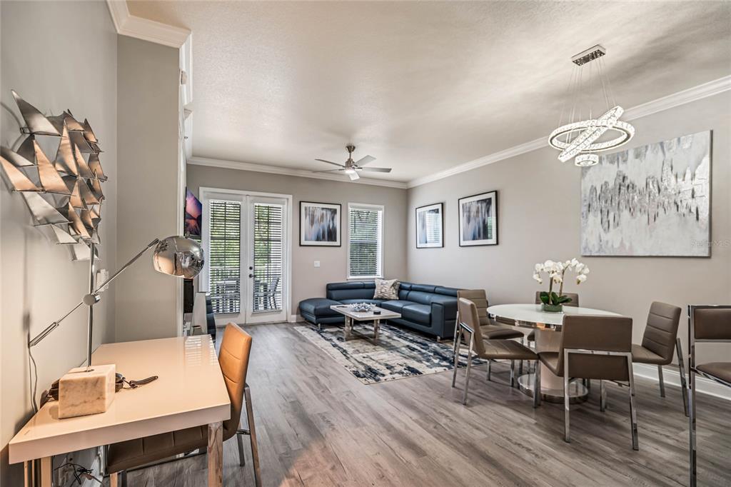 A modern open-concept living and dining area with gray wood floors and a blue sofa — 7505 MOURNING DOVE CIRCLE UNIT 303, REUNION, FL