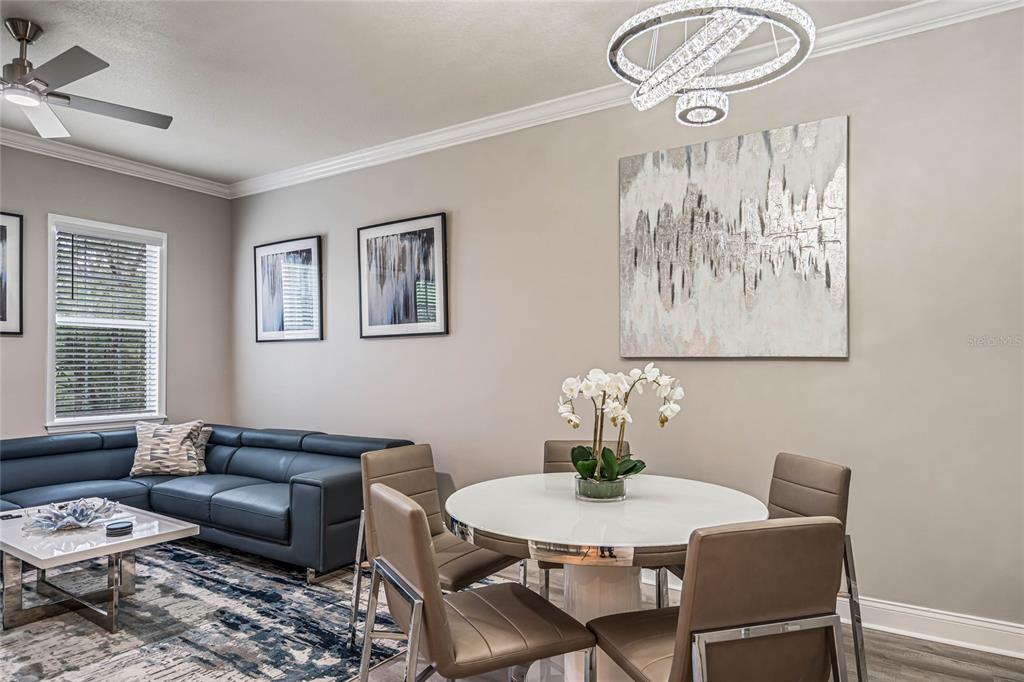 A living and dining area features a blue sectional sofa, round table, and modern chandelier — 7505 MOURNING DOVE CIRCLE UNIT 303, REUNION, FL