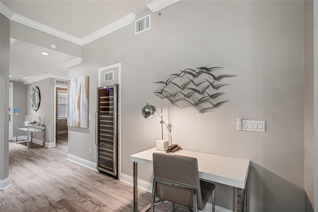 A modern home office area features a white desk, a chair, and metal wall art — 7505 MOURNING DOVE CIRCLE UNIT 303, REUNION, FL