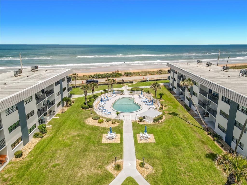 An aerial view of a beachside apartment complex with a central pool and lawn area — 2100 OCEAN SHORE BOULEVARD UNIT 2070, ORMOND BEACH, FL