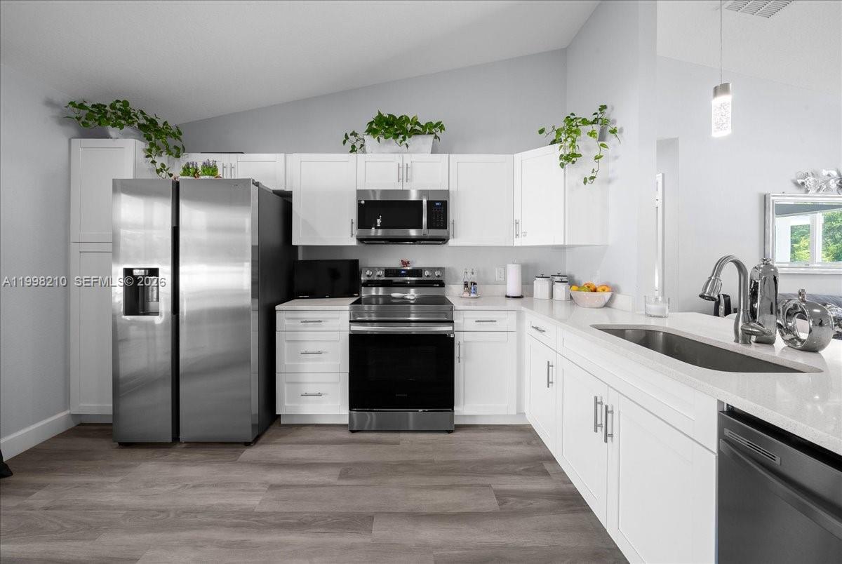 A kitchen features white cabinetry, stainless steel appliances, and light-colored countertops — 13789 102nd Pl, Ocala FL 34432, OCALA, FL