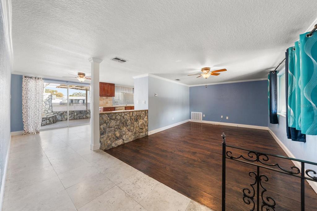 A living room with dark wood flooring, a stone-faced breakfast bar, and a tiled dining area — 4025 SAIL DRIVE, NEW PORT RICHEY, FL