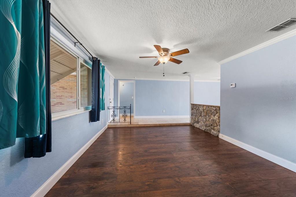 A living room features dark wood flooring, light blue walls, and a stone half-wall divider — 4025 SAIL DRIVE, NEW PORT RICHEY, FL