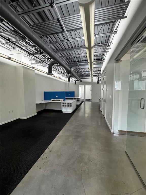 An office space features an exposed ceiling, polished concrete flooring, and built-in white desks — 1348 FRUITVILLE ROAD UNIT 203, SARASOTA, FL