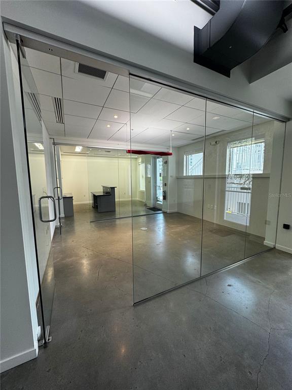 A modern office space features glass walls, polished concrete floors, and a drop ceiling — 1348 FRUITVILLE ROAD UNIT 203, SARASOTA, FL