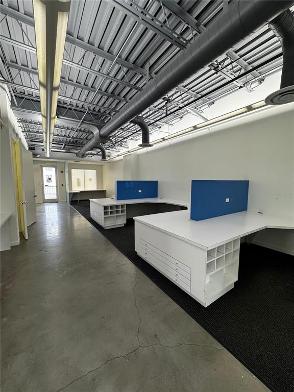 An office space features white desks with blue partitions, exposed ceiling ducts, and concrete floors — 1348 FRUITVILLE ROAD UNIT 203, SARASOTA, FL
