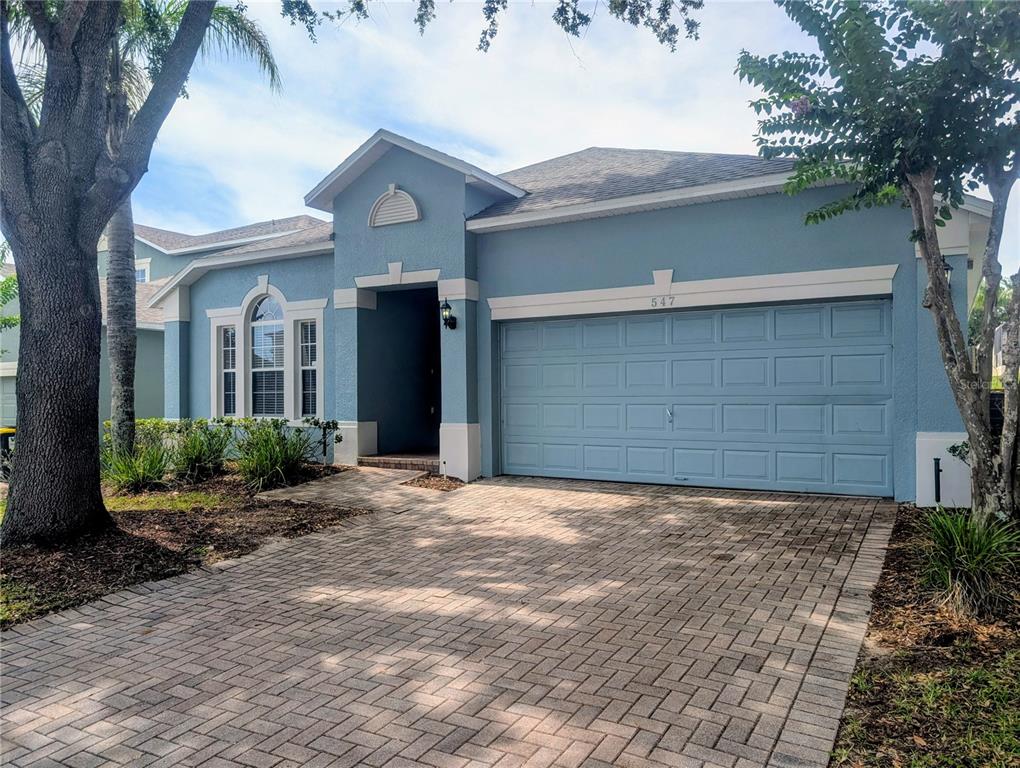A blue single-story house features a paved driveway, a two-car garage, and arched windows — 547 KENSINGTON DRIVE, DAVENPORT, FL