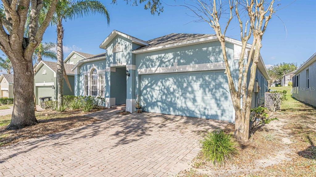 A light blue single-story house with a brick paver driveway and a two-car garage — 547 KENSINGTON DRIVE, DAVENPORT, FL
