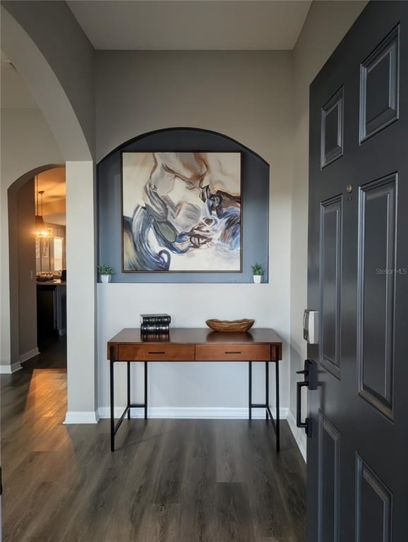 A foyer features a dark gray door, wood-look flooring, and a desk beneath an arched niche — 547 KENSINGTON DRIVE, DAVENPORT, FL